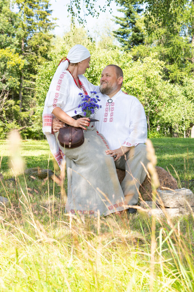 Abielupaar rahvariietes. Pruut istub peigmehe süles, noorpaar vaatab üksteisele otsa ja naeratavad